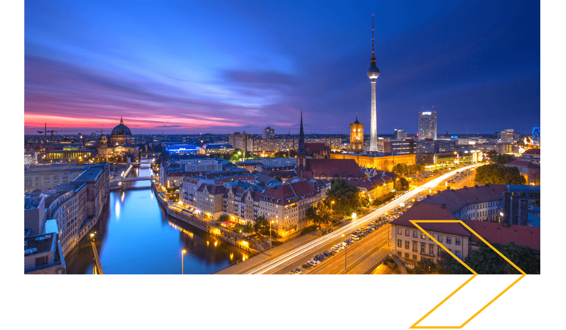 City skyline at sunset with a river to the left and a tall tower to the right. 