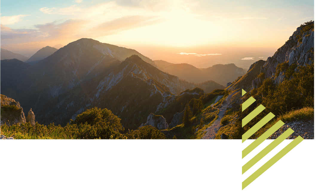 View across some mountains at sunset, with lakes visible in the distance. 