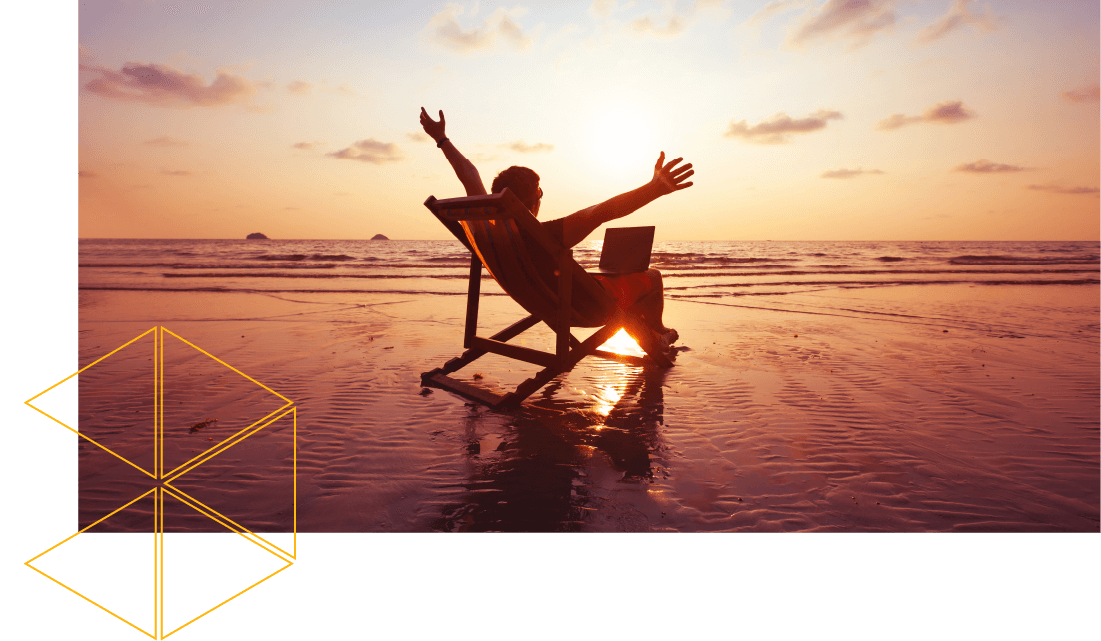 Man on a deck chair next to the sea with a laptop on his lap and his arms in the air. 