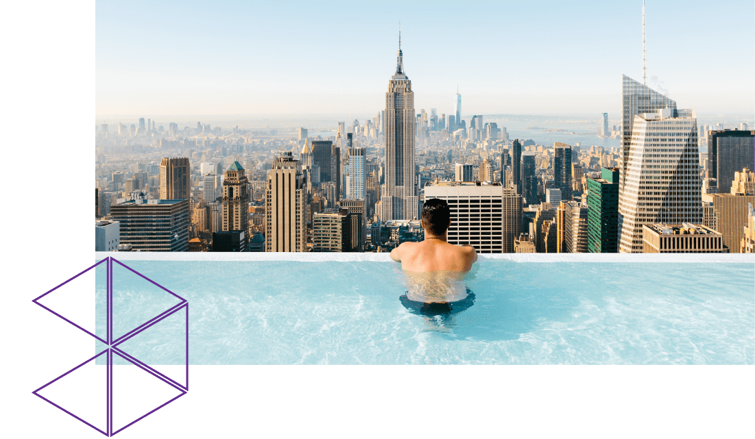 Man in a swimming pool overlooking the New York skyline.