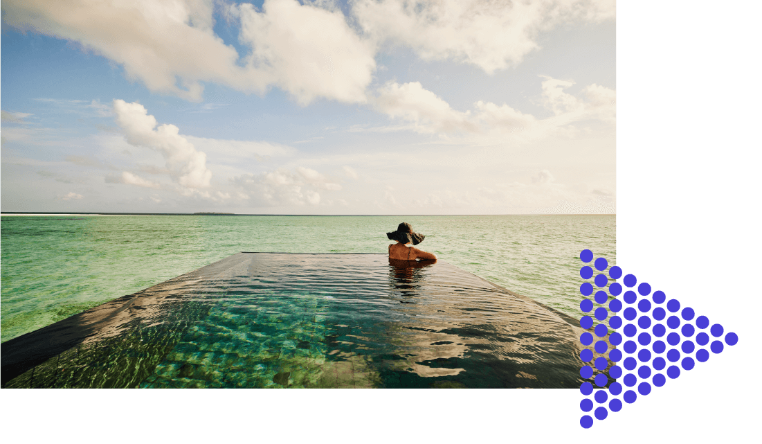 Woman wearing a sun hat in an infinity pool looking out over the ocean.  