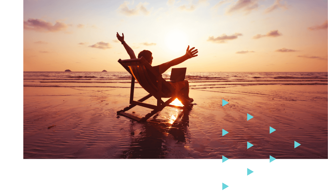 Man on a deck chair next to the sea with a laptop on his lap and his arms in the air. 