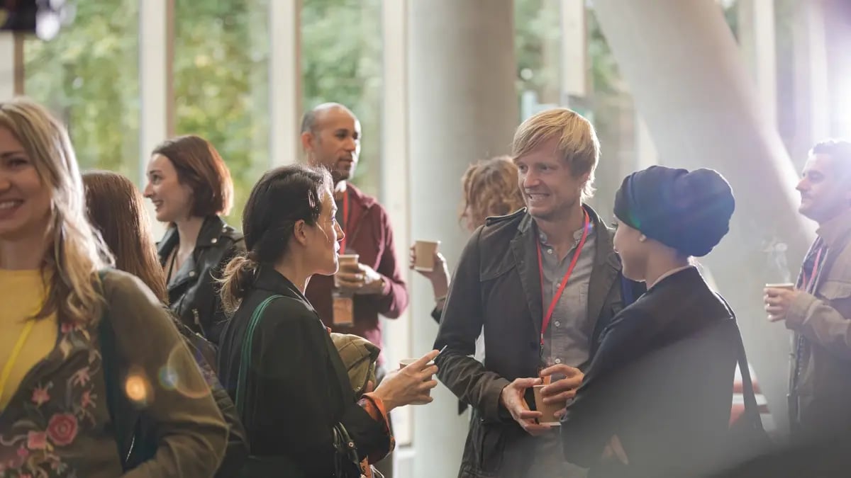Event attendees chatting at an event with a focus on three people in the center.