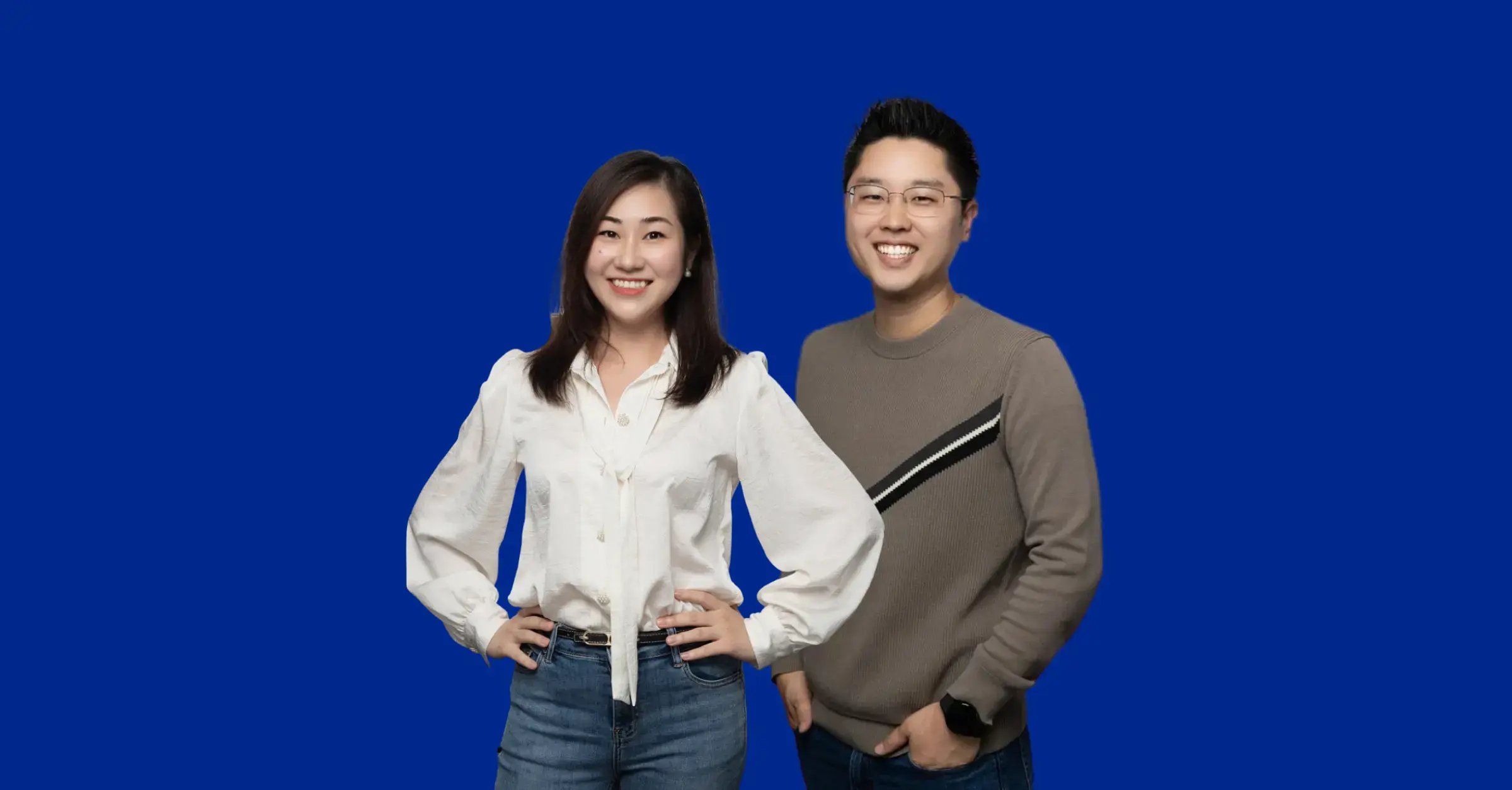 An image of an Asian lady with short dark hair, white blouse and jeans, standing next to an Asian man with a grey jumper with a stripe; both smiling and facing the camera.