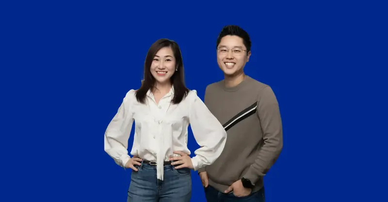 An image of an Asian lady with short dark hair, white blouse and jeans, standing next to an Asian man with a grey jumper with a stripe; both smiling and facing the camera.