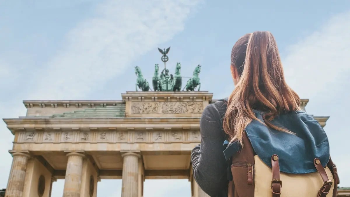 A girl with a backpack looking up towards the Brandenburg Gate in Berlin.