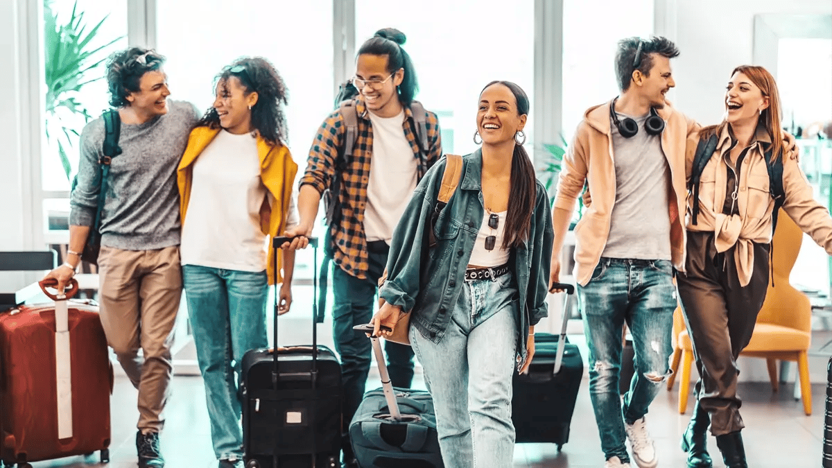 A group of smiling and laughing people with their suitcases.