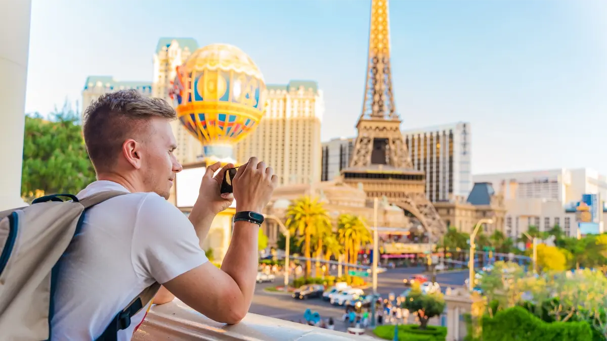 A person taking a photo of Las Vegas iconic skyline with the hot air balloon and the Eiffel Tower. 