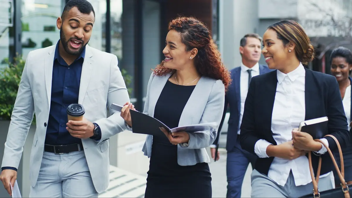 Group of people walking with documents and discussing.