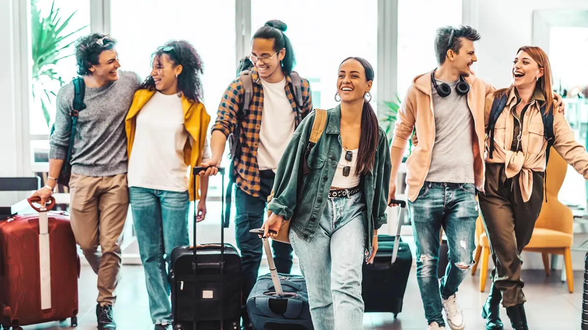A group of smiling and laughing people with their suitcases.